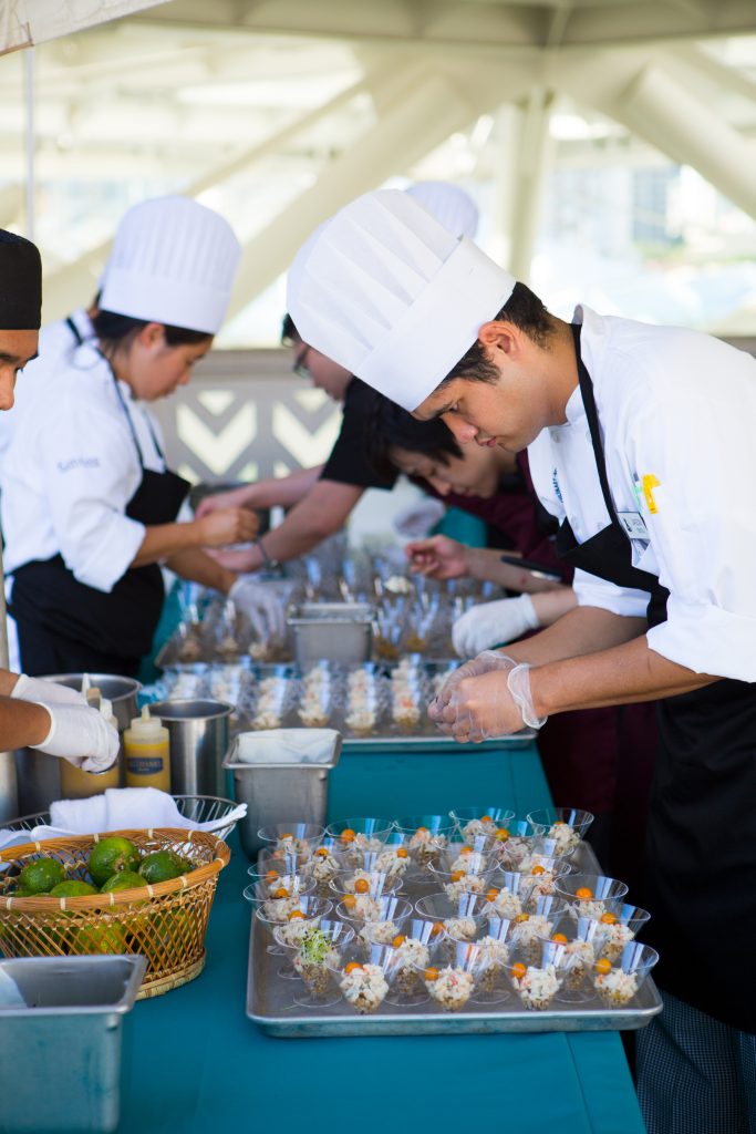 Culinary workers preparing individual serving size portions for an event. 